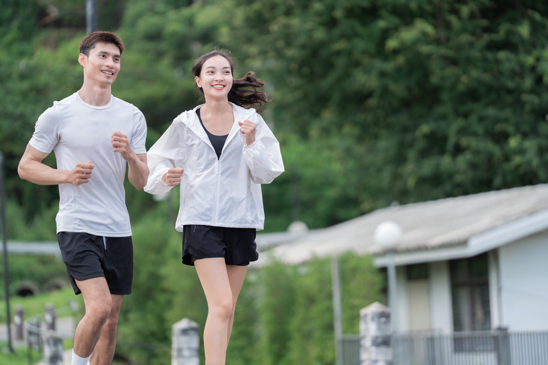 Young asian man and woman running and smiling outside, enjoying an active healthy lifestyle and outdoor sports